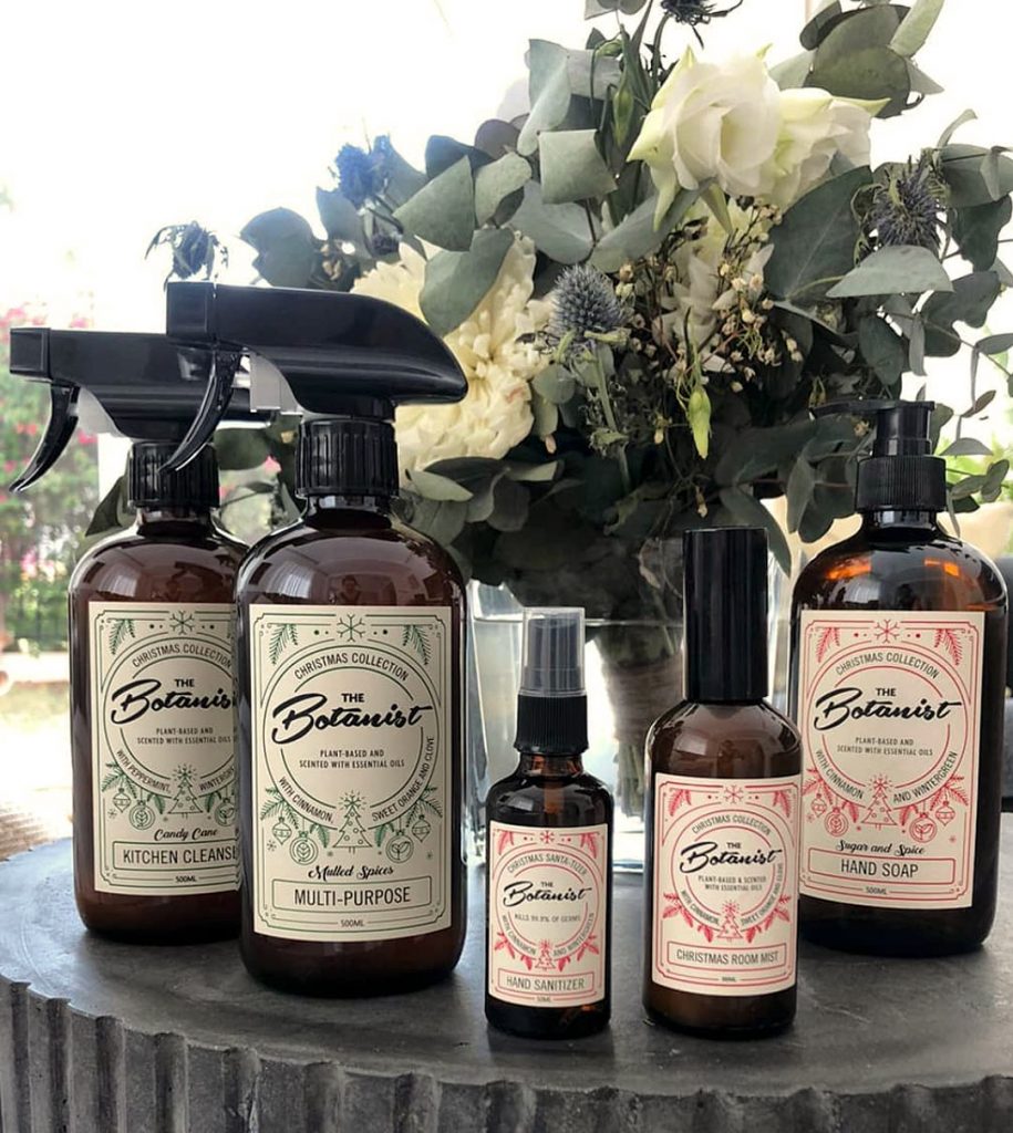 Christmas range of The Botanist cleaning products in front of some flowers and eucalyptus leaves